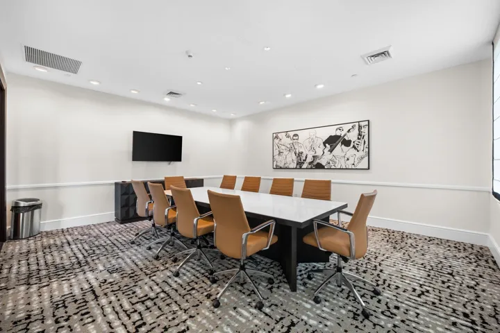 Well-appointed conference room with a large meeting table, guest seating & wall-mounted television for work or presentations.
