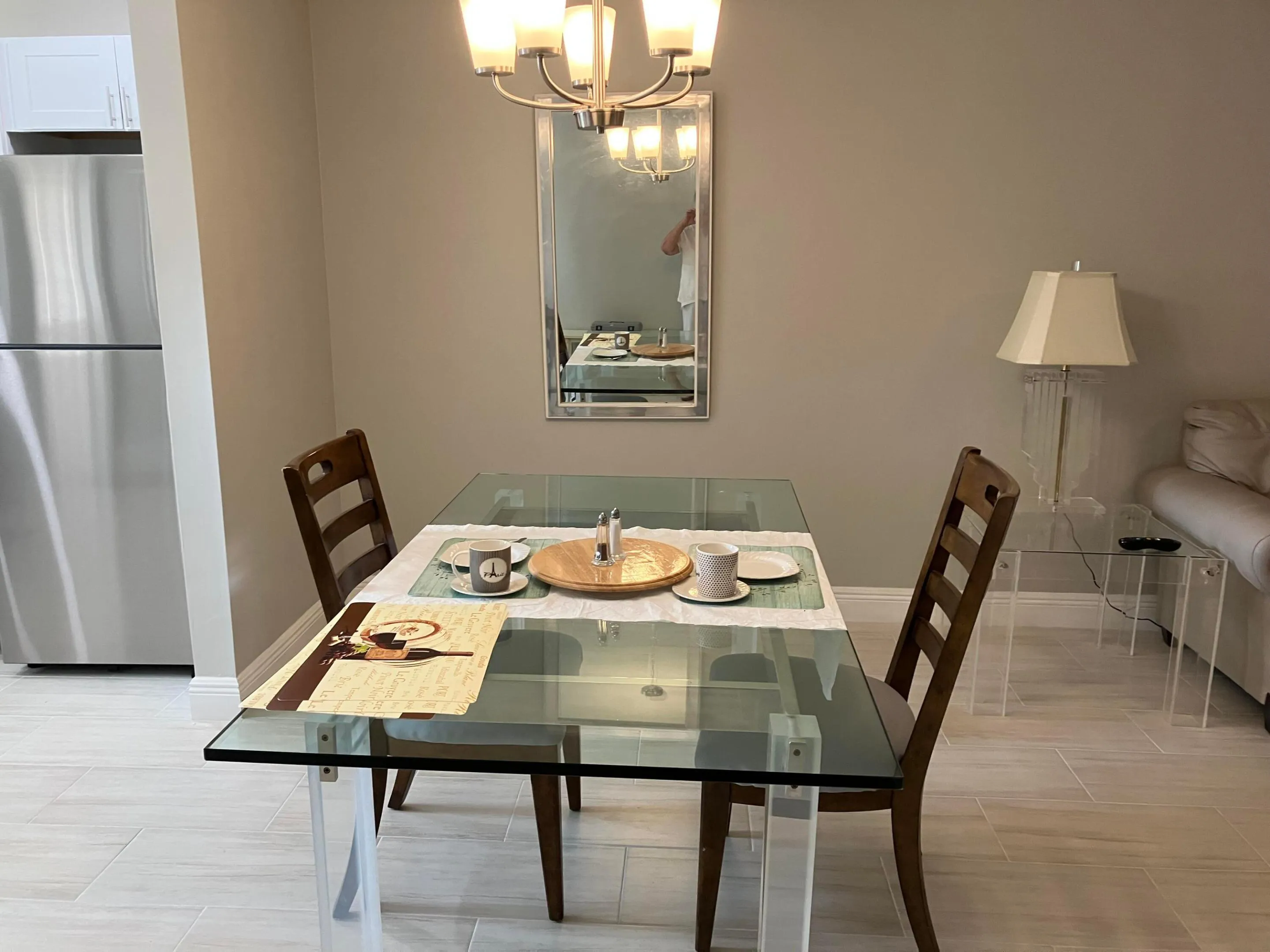 Dining space featuring a glass-top table, a four-light chandelier, and light-toned tile flooring