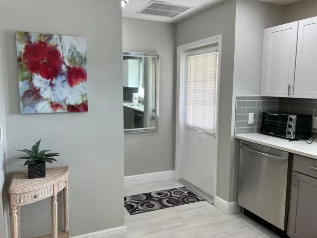 Kitchen area featuring light gray shaker cabinetry, stainless steel appliances, a light-toned countertop, and a gray subway tile backsplash