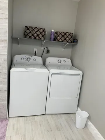 Dedicated laundry area featuring a white washing machine, white dryer, and light wood-finish flooring