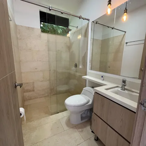 Bathroom featuring a walk-in shower with full-height stone-look tile, clear glass sliding door, and a built-in window