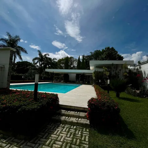 Expansive outdoor living area featuring a rectangular swimming pool with a surrounding paved deck