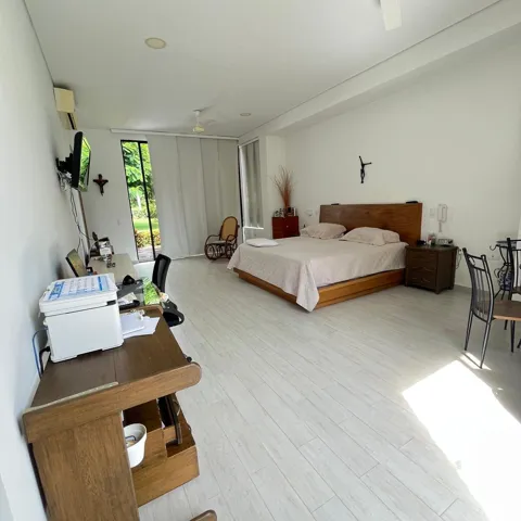 Spacious room with light wood-finish flooring, featuring a full-height window with outdoor views, white walls, and a ceiling fan