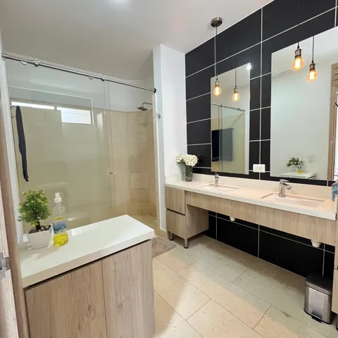 Dual vanity with undermount sinks, light wood-finish cabinetry, and contemporary wall-mounted mirrors