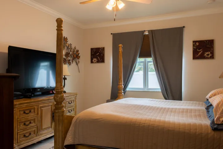 Bedroom featuring crown molding, a ceiling fan with integrated lighting, a window with blinds and dark drapery, and neutral wall tones