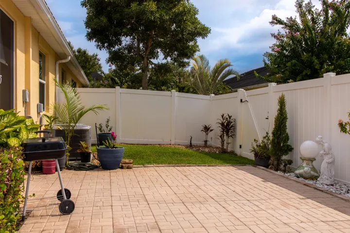 Private backyard featuring a paved patio and white privacy fencing