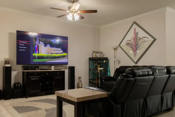 Recessed lighting illuminates crown molding and a ceiling fan with integrated lighting