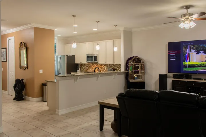 Open-concept living space featuring a kitchen with light cabinetry, stainless steel appliances, and a mosaic tile backsplash