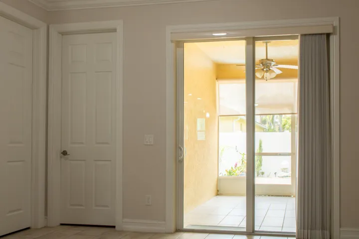 Sliding glass doors provide access to a screened patio with a ceiling fan and tiled flooring