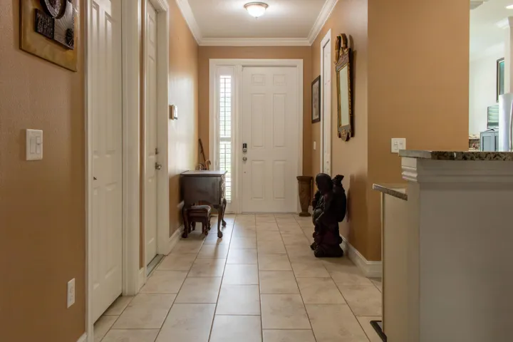 Foyer with tile flooring, crown molding, and a white paneled entry door with sidelights