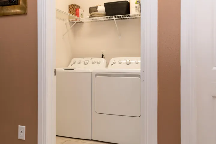 Dedicated laundry closet featuring a top-load washing machine, front-load dryer, and wire shelving