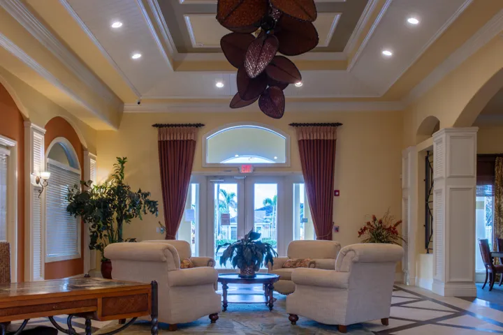Expansive common area featuring a coffered ceiling with recessed lighting, a decorative leaf-shaped ceiling fan, and large glass paneled doors