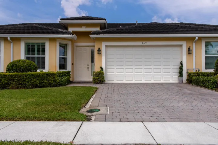 Single-story residence featuring a two-car garage, paver driveway, and stucco exterior
