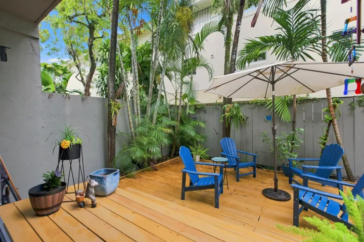 Expansive wood-finish deck surrounded by mature tropical foliage and a privacy wall