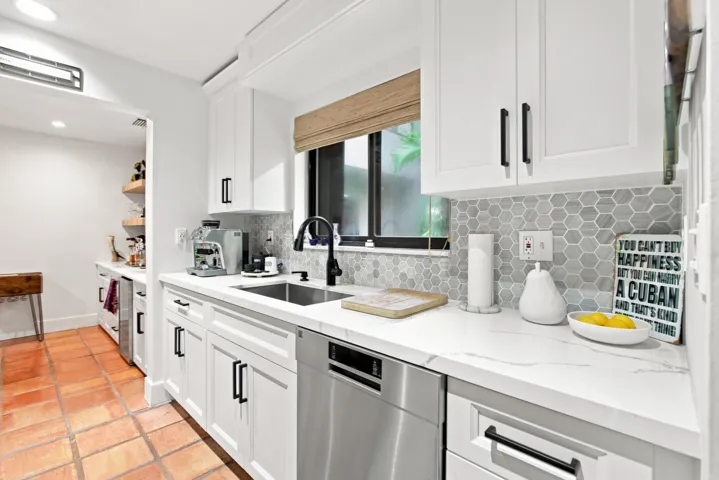 Modern kitchen featuring white shaker cabinetry, stainless steel dishwasher, hexagonal tile backsplash, white countertops, and a black gooseneck faucet