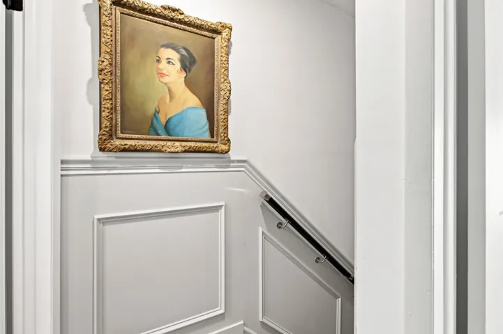 Stairwell featuring wainscoting with decorative molding, a dark handrail, and light wall paint