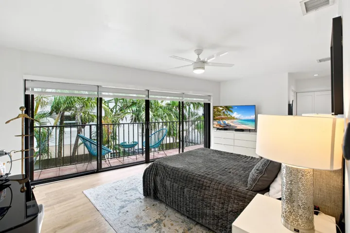 Floor-to-ceiling glass doors opening to a private balcony, complemented by a ceiling fan with integrated lighting