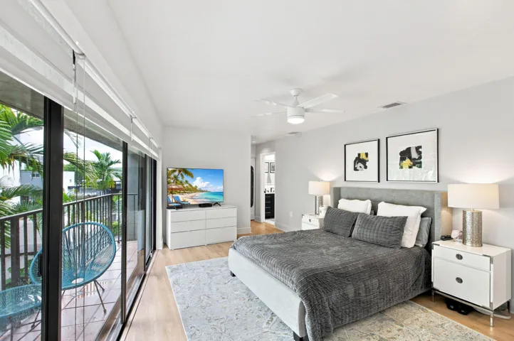 Bedroom featuring a private balcony with black metal railings, a ceiling fan, light wood-finish flooring, and a recessed doorway
