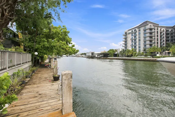 Waterfront property featuring a wooden boardwalk, mature trees, and canal access