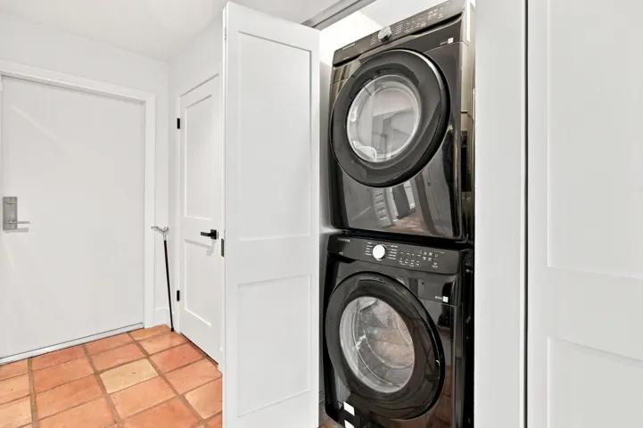Dedicated laundry closet featuring a stacked black washer and dryer unit