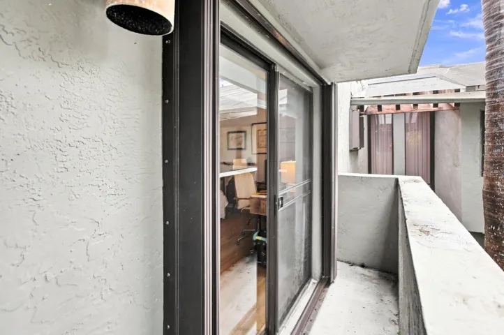 Private balcony featuring a sliding glass door entry, stucco exterior, and concrete flooring