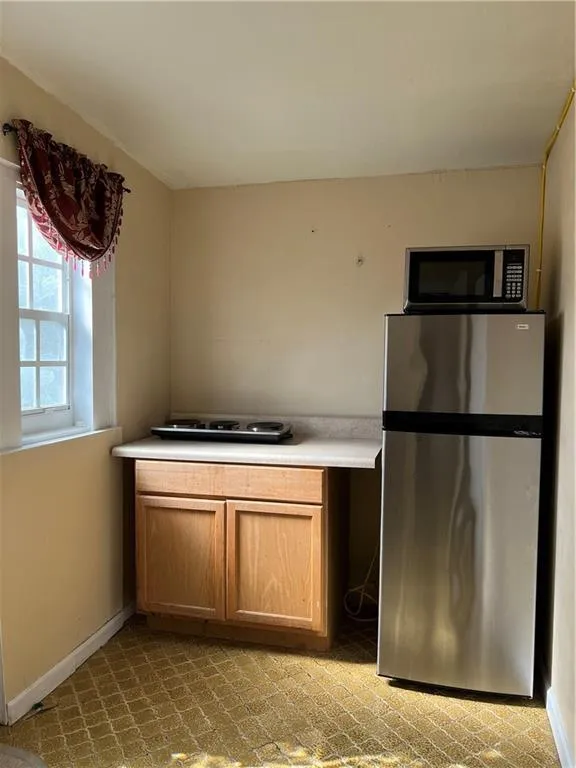 Compact kitchen area featuring a built-in base cabinet with wood-finish doors, a light-toned countertop, and a window providing natural light