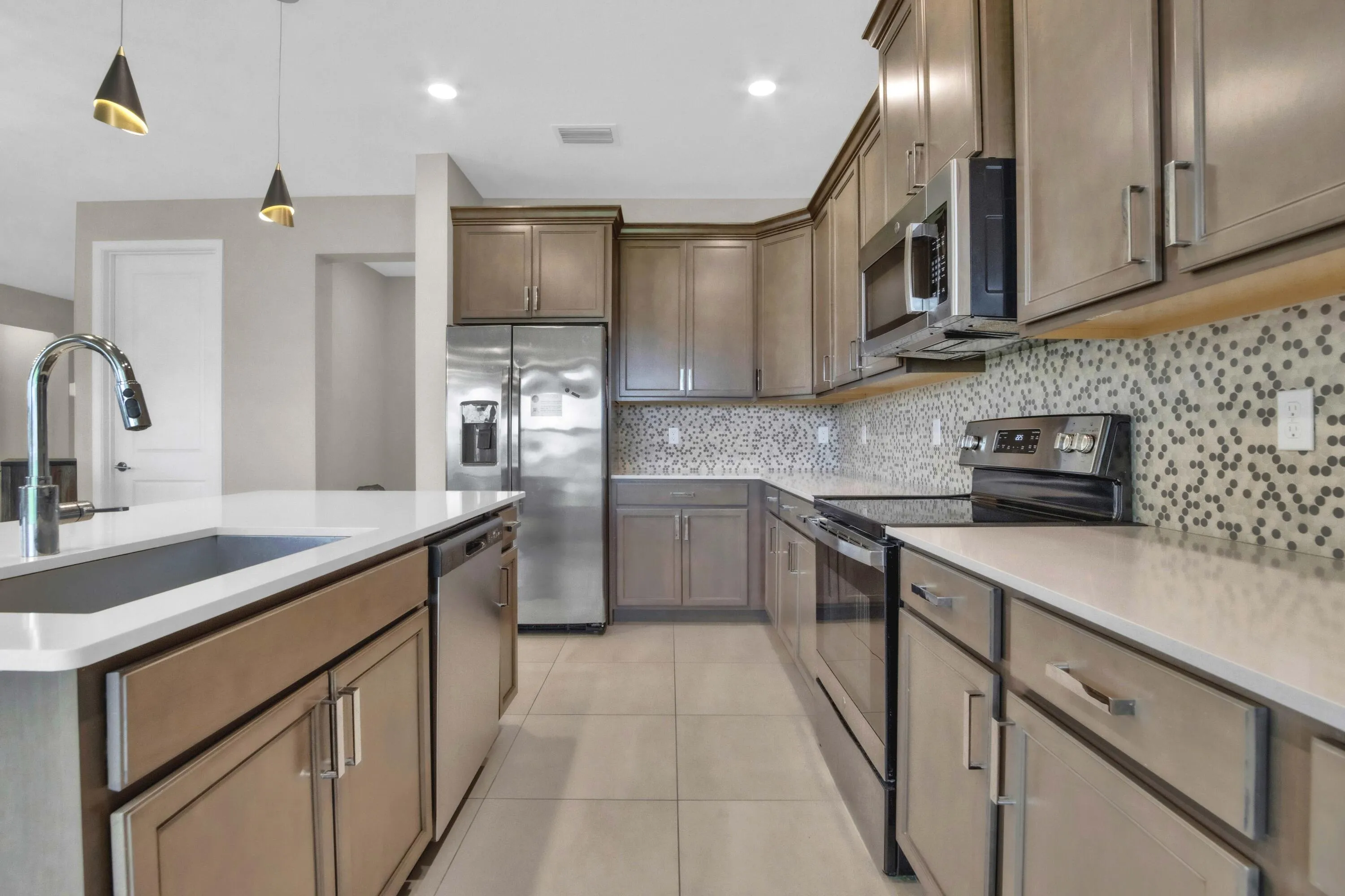 The well-appointed kitchen features rich cabinetry, stainless steel appliances, a stylish backsplash, and a generous island, ideal for both cooking and entertaining.