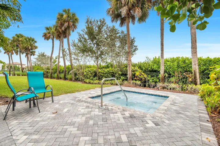 A relaxing spa is nestled among the landscaping near the pool.