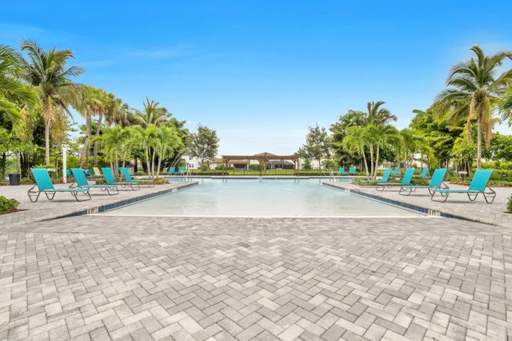 Enjoy the large resort-style community pool surrounded by palm trees and lounge chairs.