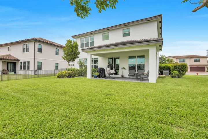 The covered patio overlooks a spacious backyard, offering a private outdoor space perfect for relaxing or entertaining.