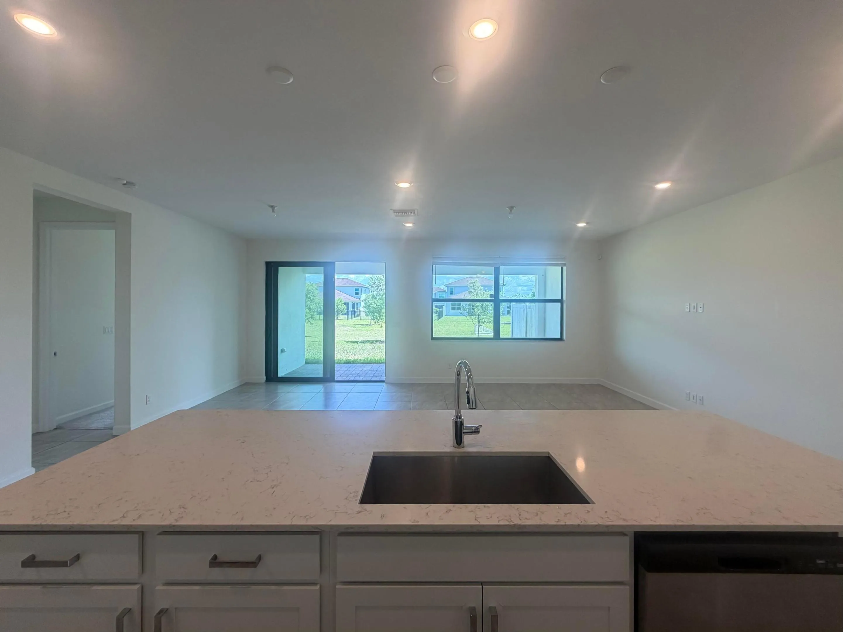 Kitchen island with a stainless steel undermount sink, gooseneck faucet, and light-toned countertop
