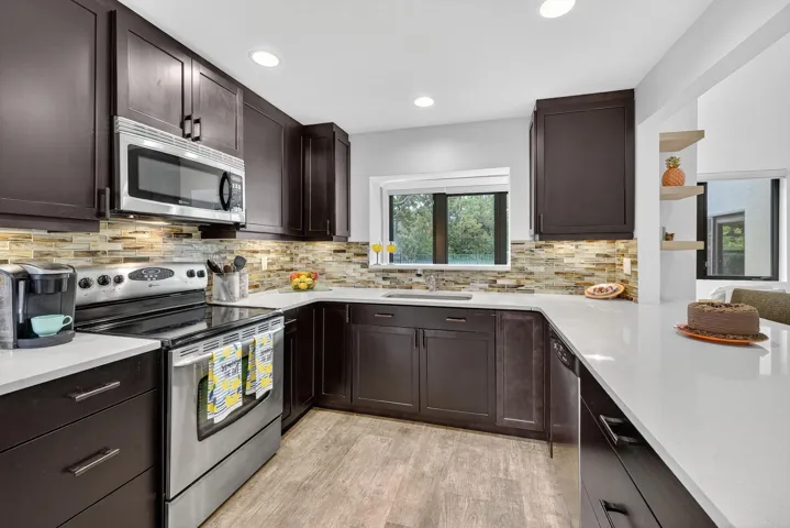 Full glass backsplash and rich coffee color cabinets.