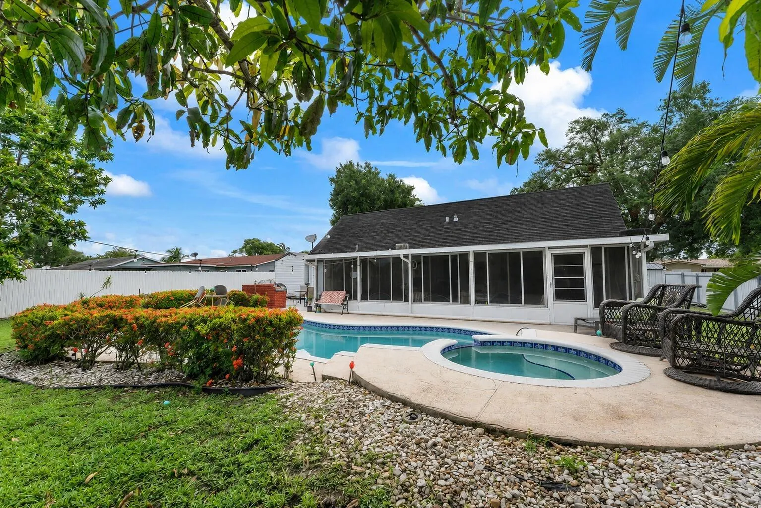 Expansive backyard featuring a fenced perimeter, a free-form pool with an integrated spa, and a screened-in patio