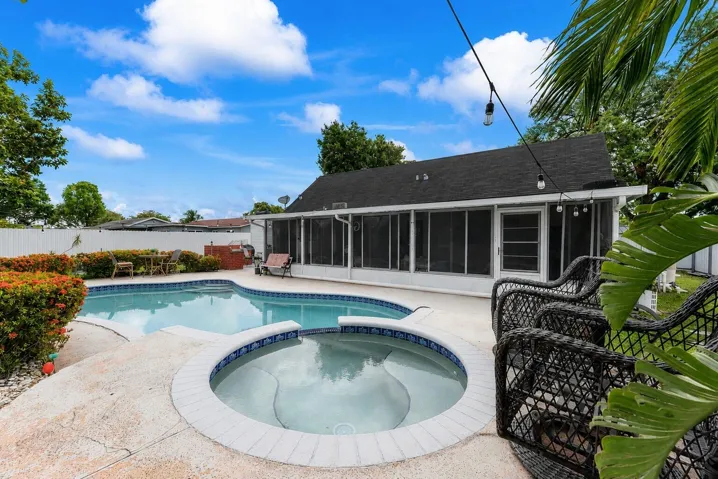 Expansive outdoor area featuring a freeform swimming pool with integrated spa, concrete decking, and lush landscaping