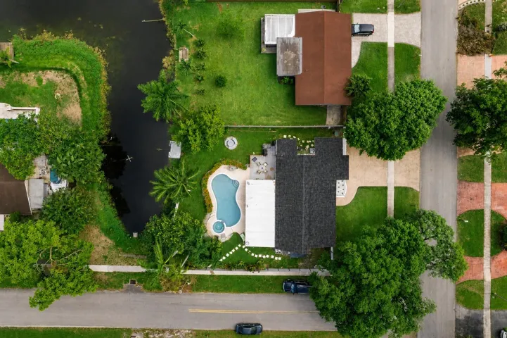 Residential property featuring a dark-shingled roof and an inviting freeform swimming pool with an integrated spa