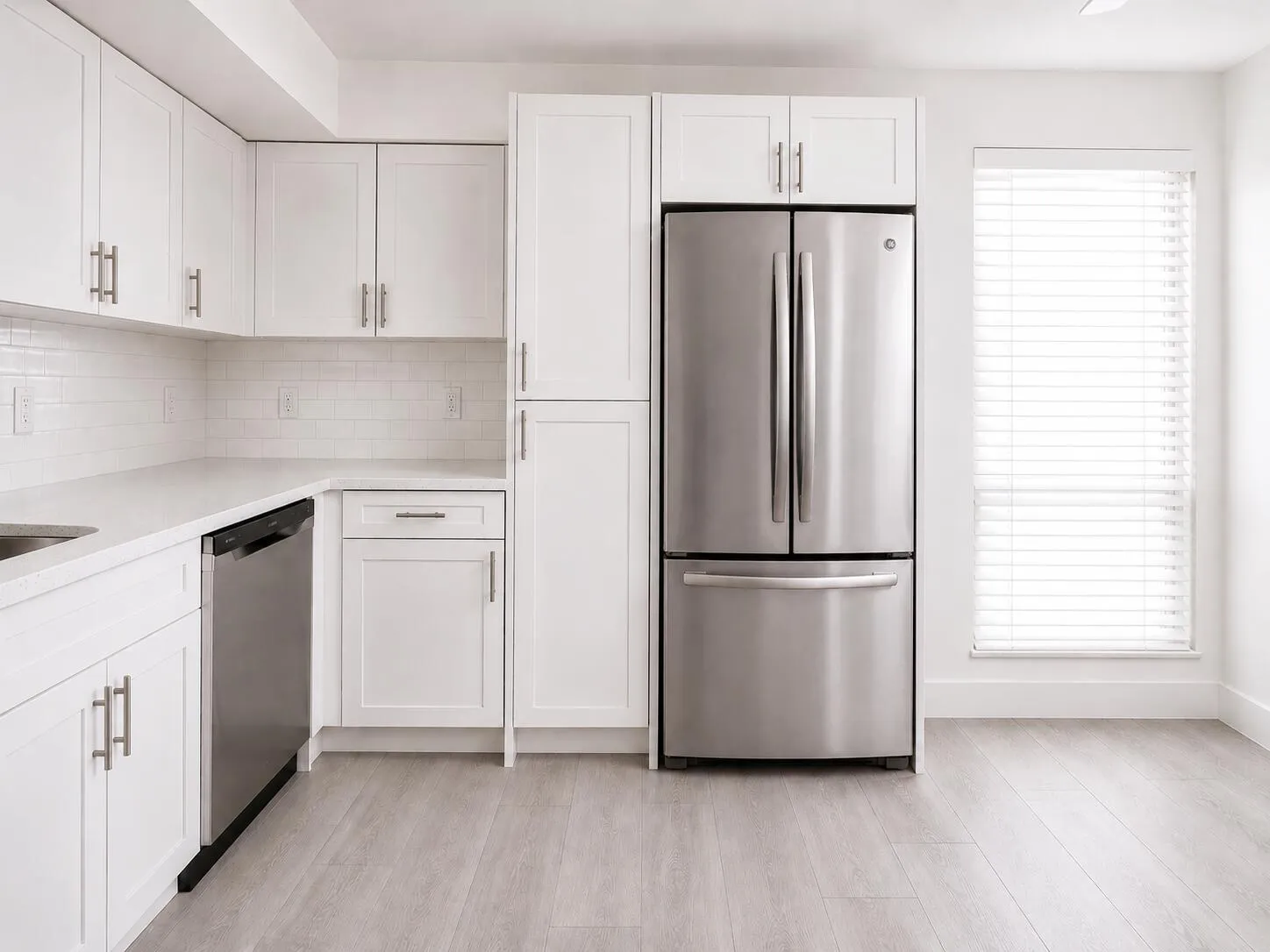 Kitchen featuring white shaker-style cabinetry, stainless steel appliances, white subway tile backsplash, light wood-finish flooring, and a window with horizontal blinds