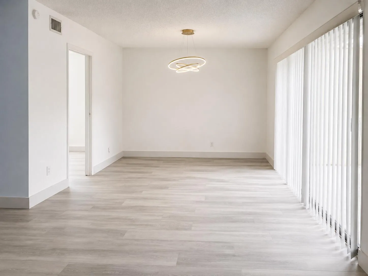 Bright interior space featuring light wood-finish flooring, white walls, and a modern circular ceiling light fixture