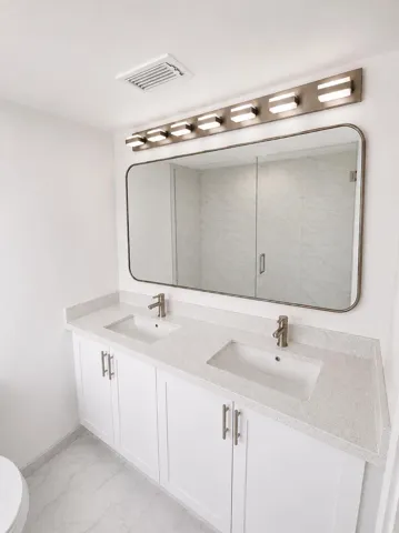 Double vanity with white cabinetry, light-toned countertops, and dual undermount sinks