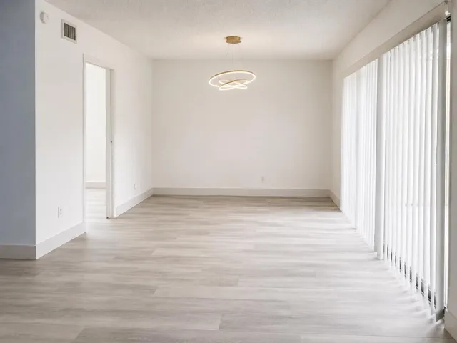 Bright interior space featuring light wood-finish flooring, white walls, and a modern circular ceiling light fixture
