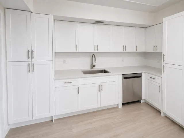 Contemporary kitchen featuring extensive white shaker cabinetry, light-toned countertops, a stainless steel dishwasher, a stainless steel sink with a gooseneck faucet, and a white subway tile backsplash