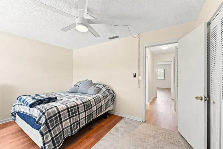 Ceiling fan with integrated lighting, wood-finish flooring, white louvered closet doors, and recessed lighting in the hallway
