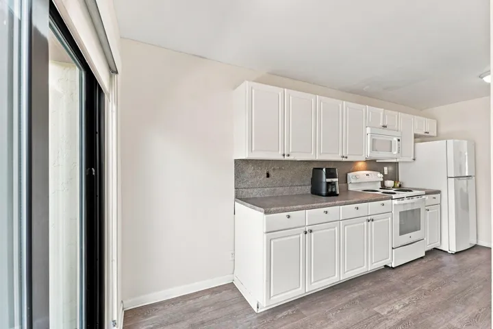 Kitchen featuring white cabinetry, gray countertops, a built-in microwave, and wood-finish flooring