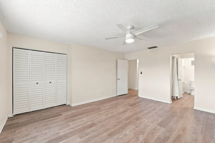 Spacious room featuring wood-finish flooring, a built-in ceiling fan with integrated lighting, louvered bi-fold closet doors, and neutral wall tones