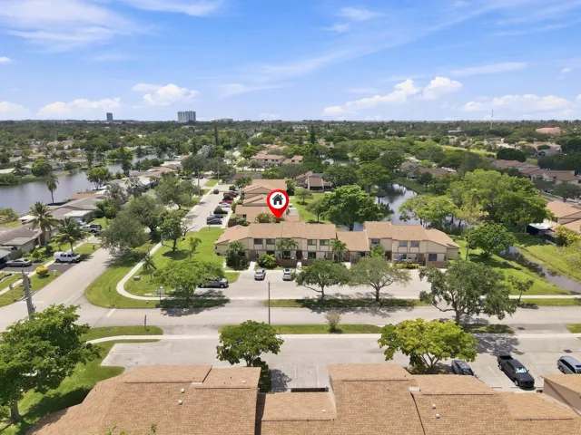 Aerial perspective showcasing a residential development with multiple units, surrounding green spaces, and bodies of water