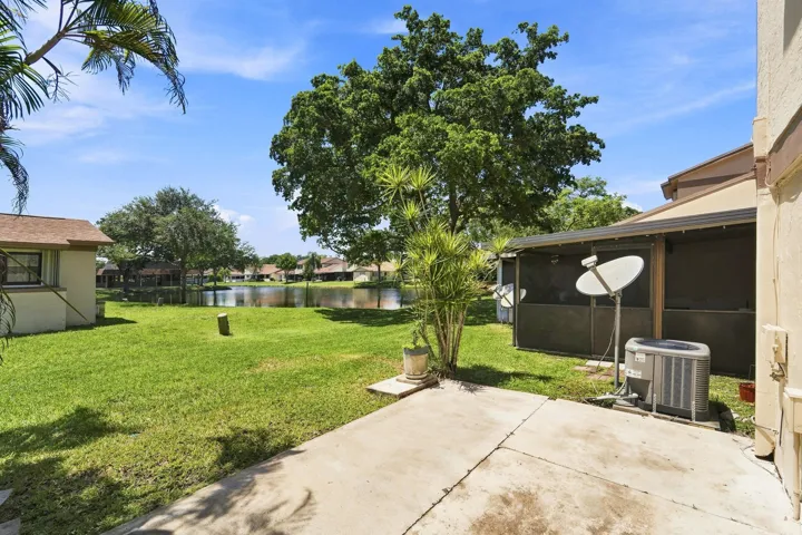 Expansive backyard featuring a manicured lawn, concrete patio, and a screened enclosure