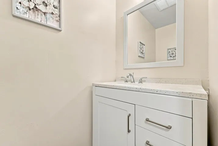 White vanity with brushed nickel hardware, integrated sink, and a framed mirror