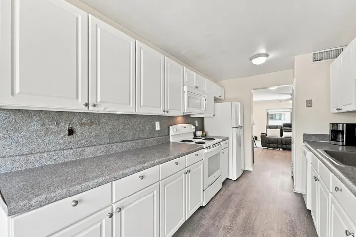 Galley kitchen featuring white cabinetry, gray countertops, and wood-finish flooring