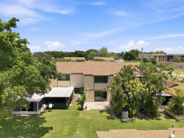 Expansive backyard featuring a manicured lawn, screened-in patio, and mature trees