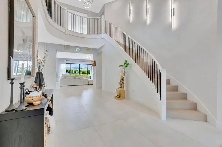 Dramatic entry foyer featuring a sweeping staircase, soaring ceilings, and abundant natural light.