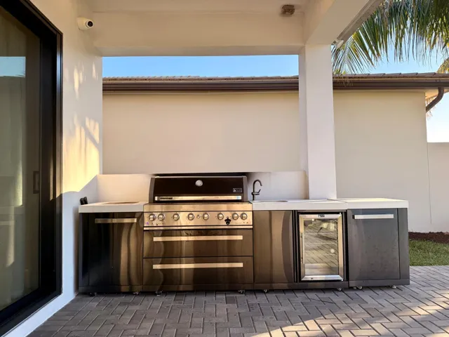 Covered outdoor kitchen equipped with built-in grill, storage, and counter space for year-round outdoor entertaining.